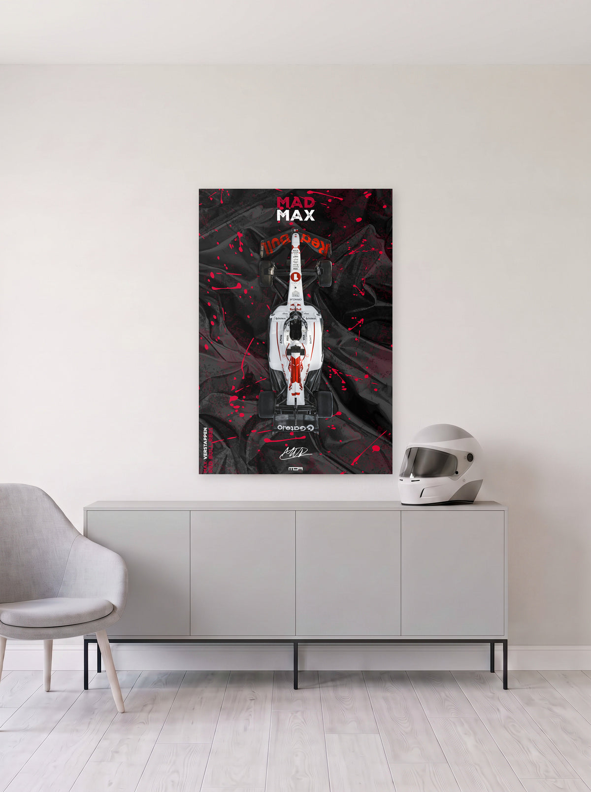 Poster del Red Bull de Max Verstappen con el rotulo Mad Max arriba y salpicaduras rojas, colgado en la pared clara de un salon, sobre un aparador gris con un casco de competicion al lado, decoracion racing de MOA-Grafics.