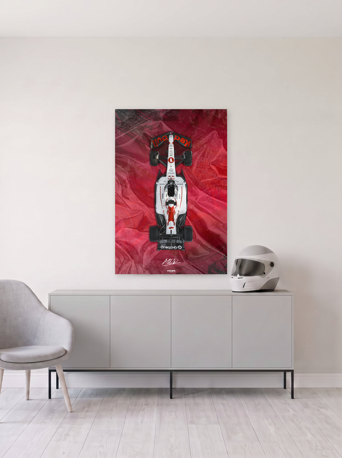 Poster del Red Bull de Max Verstappen sobre fondo rojo satinado, colgado en la pared clara de un salon, sobre un aparador gris con un casco de competicion al lado, decoracion racing de MOA-Grafics.
