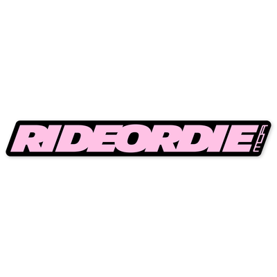 Diseño plano de una barra negra inclinada y muy alargada con el lema RIDEORDIE en cursiva pesada rosa claro y sin espacios entre palabras, y el rótulo MOA en pequeño al final, girado para seguir la inclinación.