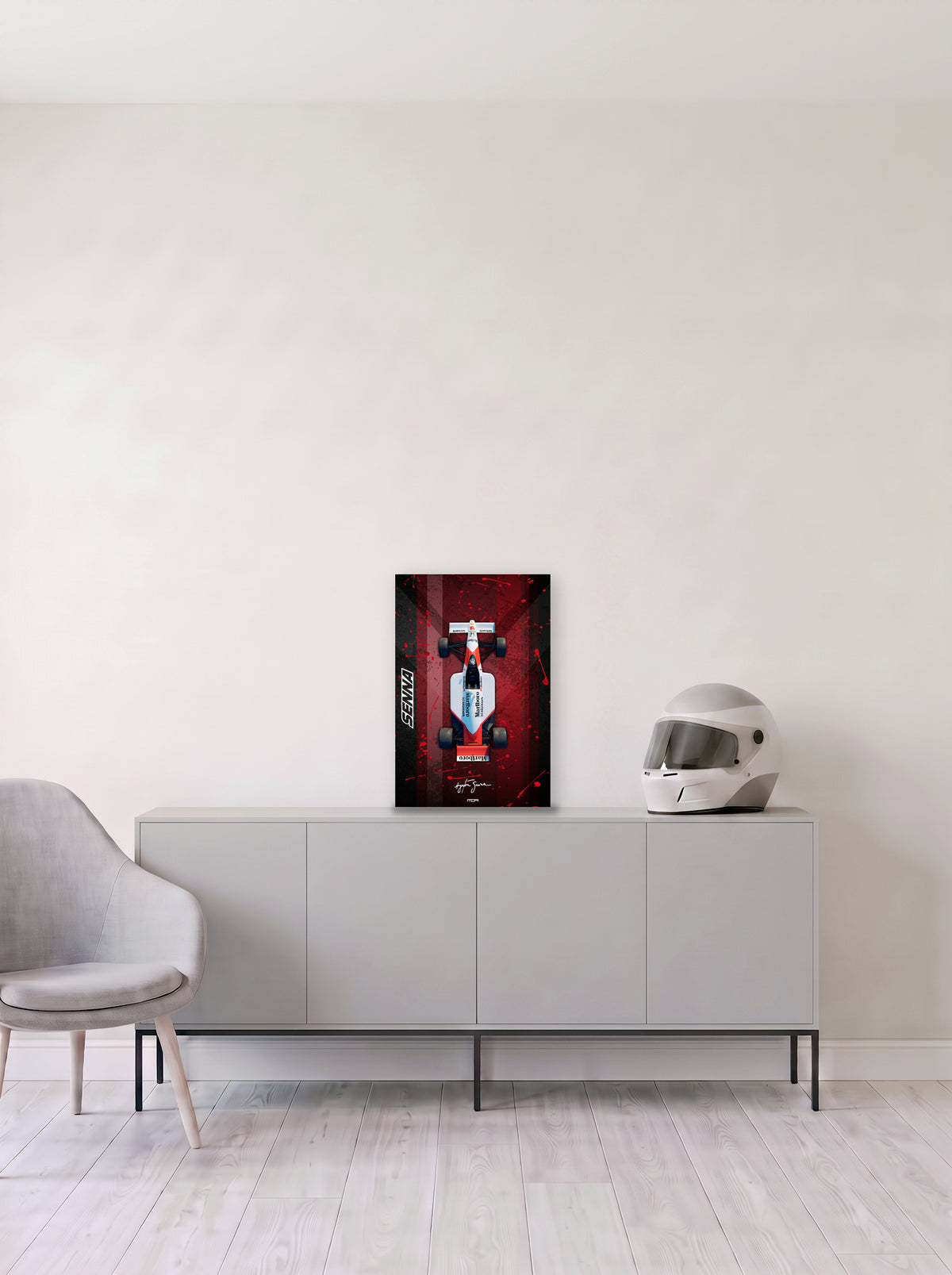 Poster del McLaren MP4/6 de Ayrton Senna con salpicaduras sobre fondo rojo, en medida 33,3 x 50 cm, apoyado sobre un aparador gris junto a un casco de competicion, decoracion racing de MOA-Grafics.
