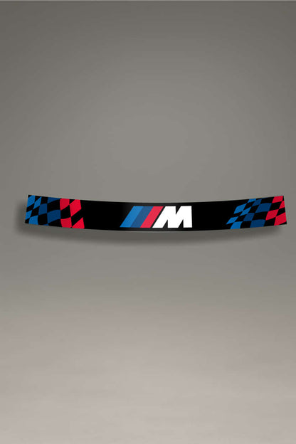Parasol de vinilo negro para parabrisas, con logo M de BMW y extremos de bandera de carreras a cuadros en rojo y azul. Ideal para un look de competición y protección solar.