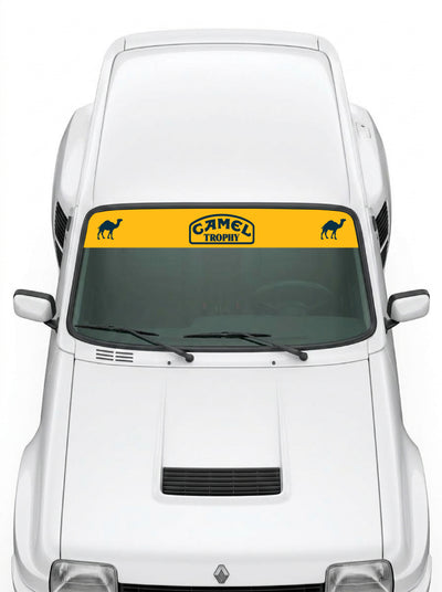 Coche con el parasol de vinilo Camel amarillo con el sello Camel Trophy en el centro y los camellos a los dos lados instalado en el parabrisas