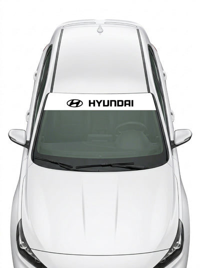 Parasol de vinilo Hyundai blanco con el emblema oval y el lettering HYUNDAI en negro, instalado en el parabrisas de un Hyundai blanco