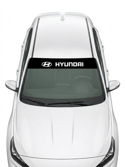 Parasol de vinilo Hyundai negro con el emblema oval y el lettering HYUNDAI en blanco, instalado en el parabrisas de un Hyundai blanco