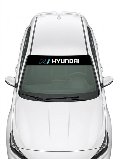 Parasol de vinilo Hyundai N negro con el logo N en azul y el lettering HYUNDAI en blanco, instalado en el parabrisas de un Hyundai blanco