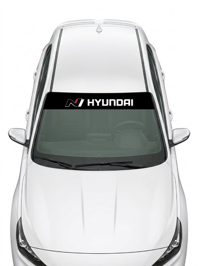 Parasol de vinilo Hyundai N negro con el logo N en rojo y el lettering HYUNDAI en blanco, instalado en el parabrisas de un Hyundai blanco