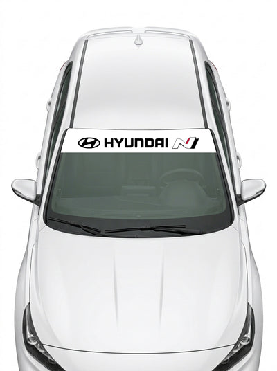 Parasol de vinilo Hyundai N blanco con el emblema, el lettering HYUNDAI y el logo N, instalado en el parabrisas de un Hyundai blanco