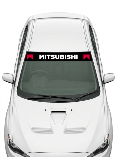 Coche con el parasol de vinilo Mitsubishi negro con el lettering MITSUBISHI en blanco y los banderines rojos de la livrea de rally instalado en el parabrisas