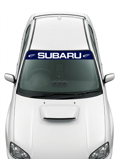 Coche con el parasol de vinilo Subaru azul marino con el lettering SUBARU y el emblema de las Pleyades a los dos lados en blanco instalado en el parabrisas