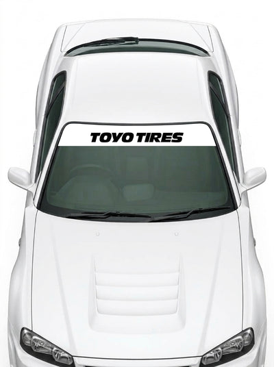 Coche con el parasol de vinilo Toyo Tires blanco con el lettering TOYO TIRES en negro instalado en el parabrisas