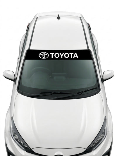 Coche con el parasol de vinilo Toyota negro con el emblema de los tres ovalos y el lettering TOYOTA en blanco instalado en el parabrisas