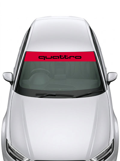Parasol de vinilo Audi Quattro de 150x25 cm en rojo con el lettering quattro en negro, instalado en el parabrisas de un coche