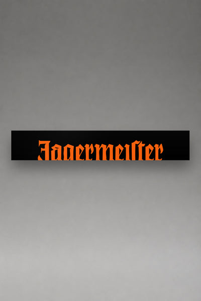Parasol de vinilo Jagermeister negro con el lettering gotico de la marca en naranja, la tira entera de 150 x 25 cm vista de frente, de MOA-Grafics.