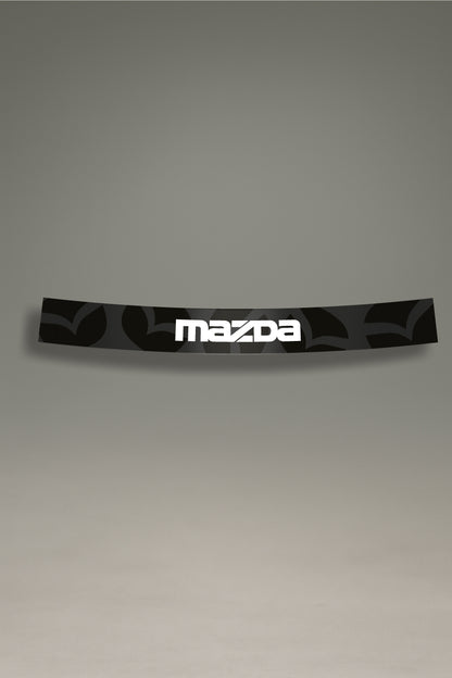 Parasol de vinilo con un patrón del emblema de Mazda en gris oscuro y el logotipo en blanco. Un accesorio de diseño de MOA-Grafics para personalizar y proteger el parabrisas.

