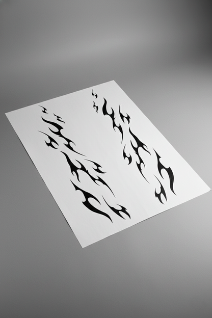 Pliego de vinilo del kit tribal en color negro, visto en perspectiva sobre mesa gris. Muestra del producto físico para instalación en coche.