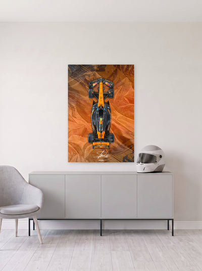 Poster del McLaren de Lando Norris sobre fondo naranja satinado, colgado en la pared clara de un salon, sobre un aparador gris con un casco de competicion al lado, decoracion racing de MOA-Grafics.