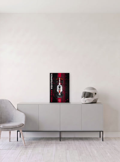 Poster del Red Bull de Max Verstappen con el rotulo Mad Max en vertical sobre franja roja, en medida 33,3 x 50 cm, apoyado sobre un aparador gris junto a un casco de competicion, decoracion racing de MOA-Grafics.
