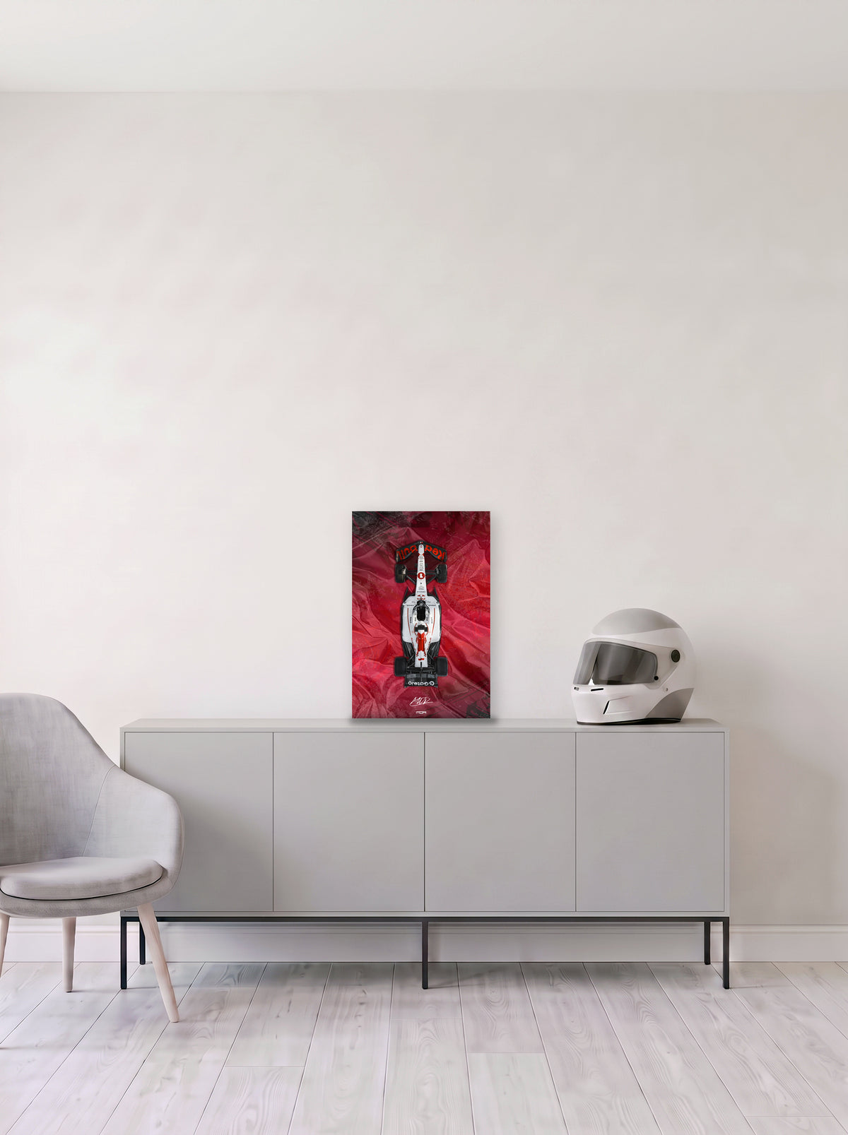 Poster del Red Bull de Max Verstappen sobre fondo rojo satinado, en medida 33,3 x 50 cm, apoyado sobre un aparador gris junto a un casco de competicion, decoracion racing de MOA-Grafics.