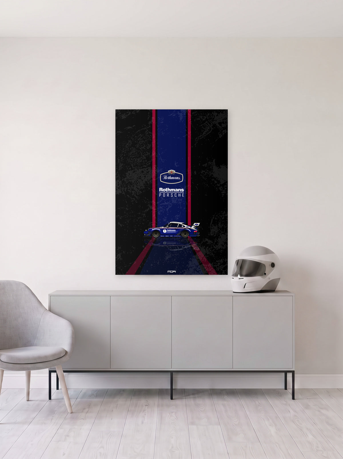 Poster del Porsche 911 Rothmans sobre fondo negro, colgado en la pared clara de un salon, sobre un aparador gris con un casco de competicion al lado, decoracion racing de MOA-Grafics.
