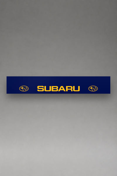 Parasol de vinilo Subaru azul con el lettering SUBARU y los emblemas de las Pleyades en amarillo, la tira entera de 150 x 25 cm vista de frente, de MOA-Grafics.